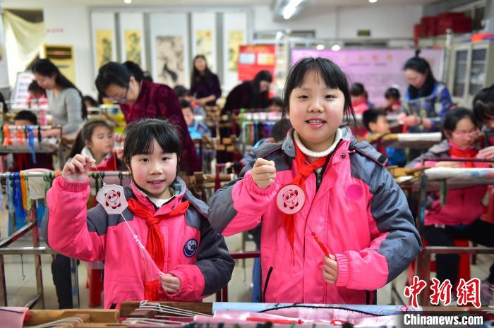 圖為小學(xué)生展示繡制好的2022年北京冬奧會(huì)吉祥物“冰墩墩”形象。　喻云亮 攝