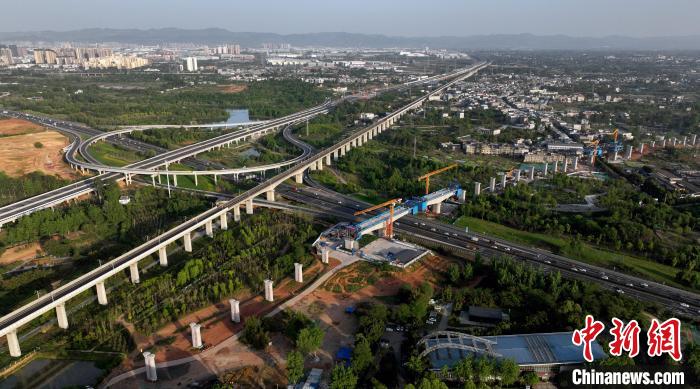 航拍正在建設的跨越成都繞城高速公路連續(xù)梁施工現(xiàn)場，旁邊依次為已運營的成渝高速鐵路和機場高速公路?！⒅铱?攝