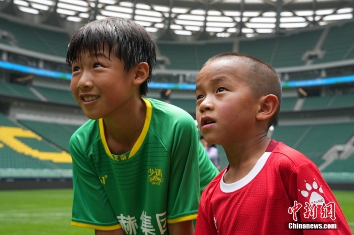 圖為北京國安小球員陳小北和7歲的俄金仁增在一起觀看場(chǎng)內(nèi)播放的紀(jì)錄片。<a target='_blank' href='/' _fcksavedurl='/'><p  align=