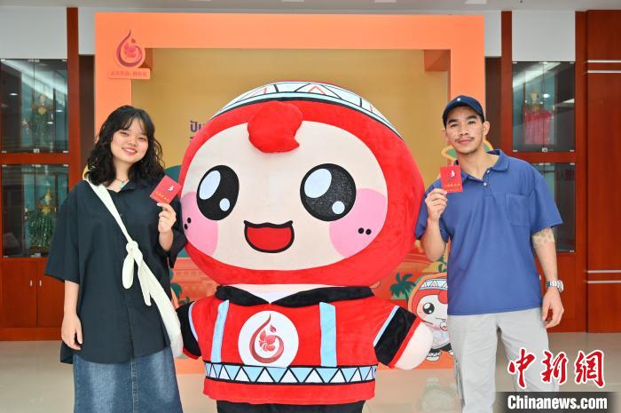 圖為泰國(guó)留學(xué)生手持獻(xiàn)血證與人偶合影?！∮峋?攝