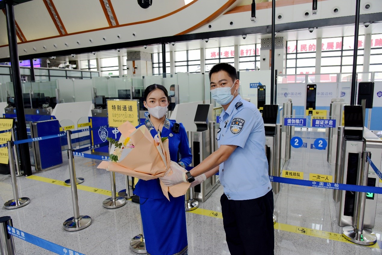 磨憨出入境邊防檢查站民警為中老鐵路第100萬(wàn)名出入境旅客，D888次國(guó)際旅客列車(chē)?yán)蠐爰藙?wù)員森達(dá)拉·妮緹婭（Sengdala Nitiya），送上鮮花。黃遠(yuǎn)飛 攝