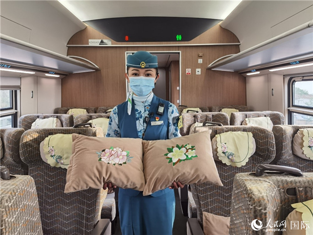 趙瑩靜展示中老鐵路國際旅客列車里帶有中國牡丹花和老撾占巴花刺繡圖案的靠墊。人民網記者 杜明明攝