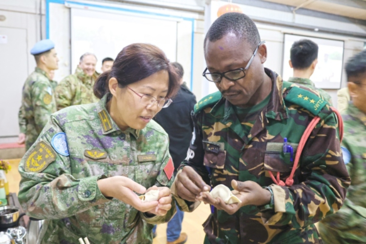 圖為維和官兵與外軍人員共同包餃子。胡光明攝