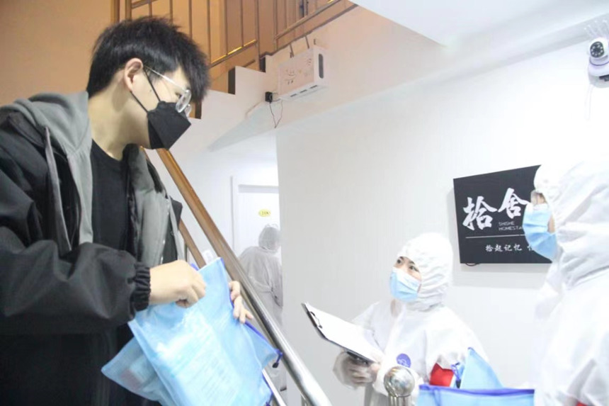 社區(qū)工作人員和志愿者身穿防護(hù)服上門送馬應(yīng)龍大健康防疫包。徐帥攝