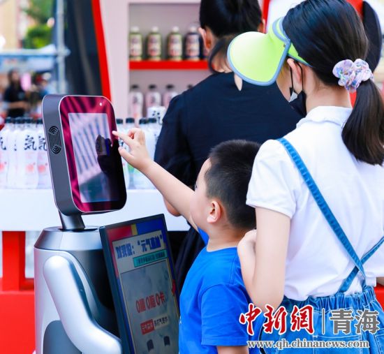 圖為一名小朋友正在和機器人“志愿者”進行互動。 沐聞 攝