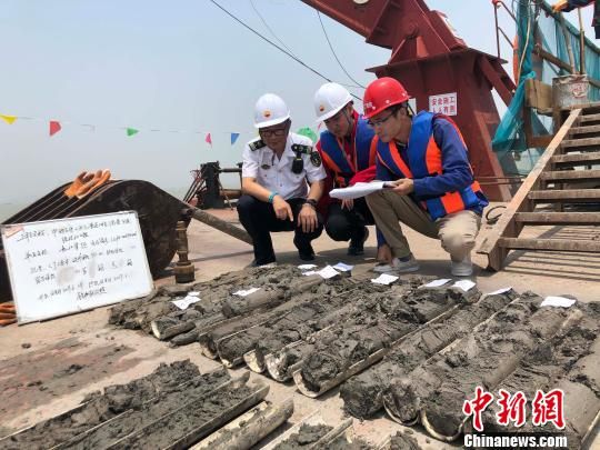 圖為勘察設(shè)計人員與海事局工作人員查看巖芯情況。　魏震 攝