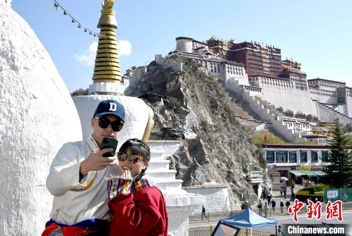 4月17日，游客身著藏式元素服裝在拉薩布達(dá)拉宮觀景臺(tái)拍照留念。　李林 攝