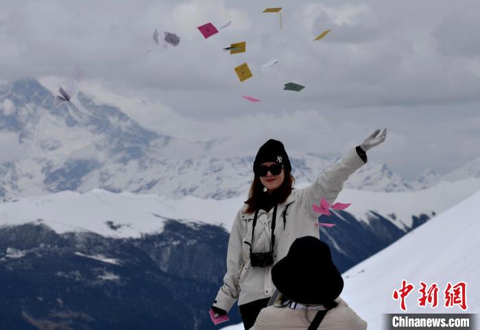 圖為5月14日，游客在西藏林芝色季拉山觀景臺(tái)拋灑“隆達(dá)”(風(fēng)馬旗，藏族民眾的一種祈福方式)?！±盍?攝