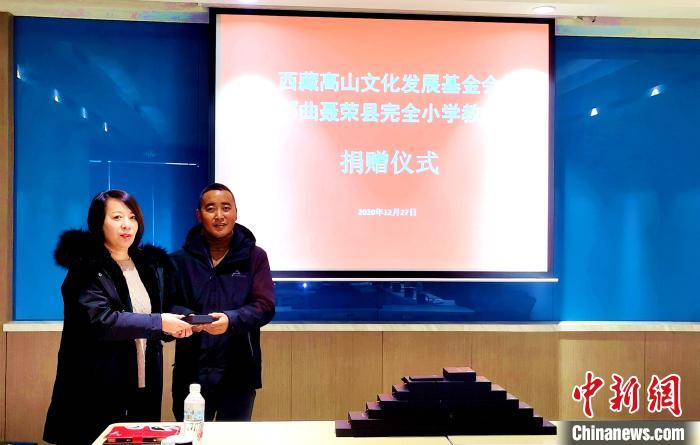 圖為西藏高山文化發(fā)展基金會(huì)理事長(zhǎng)溫麗向聶榮縣完全小學(xué)負(fù)責(zé)人捐助儀器?！∮谫e 攝