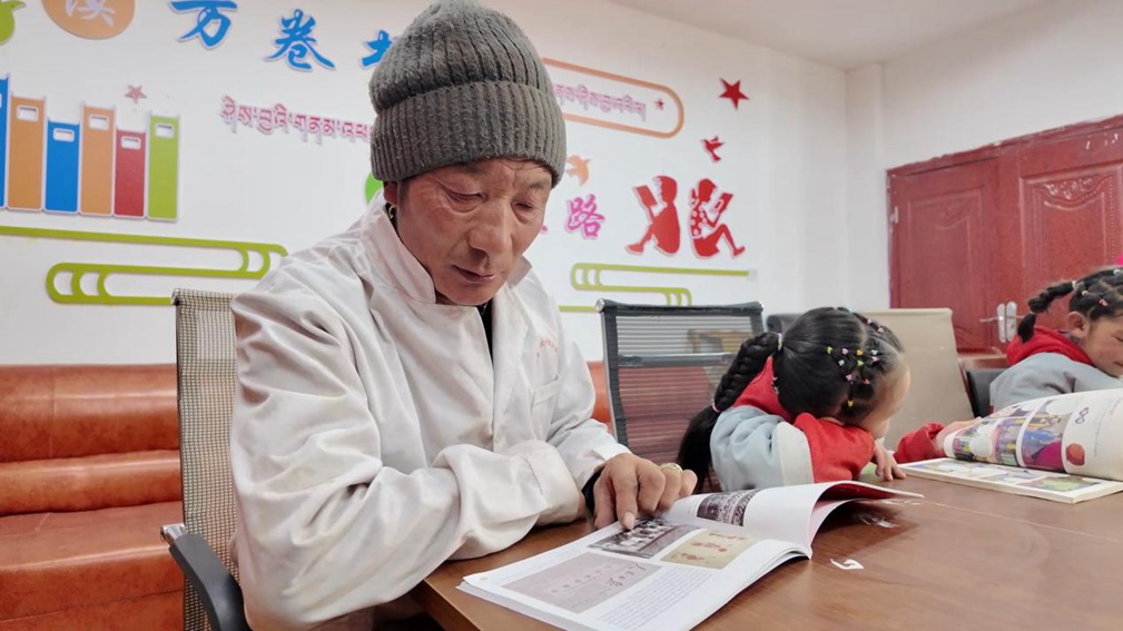 一位當?shù)卮迕窈秃⒆觽冊谀良視堇锉M情享受閱讀時光。申扎縣融媒體中心供圖