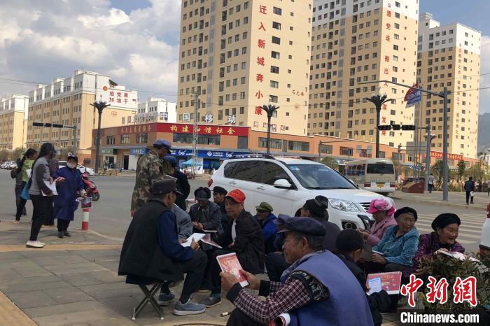圖為會澤縣城易地扶貧搬遷安置點內(nèi)，老人們聚在廣場上聊天，身后是他們的新家。　繆超 攝