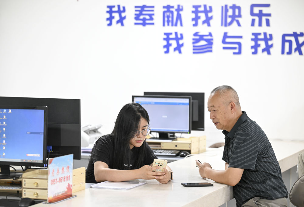 2024年6月20日，在寧夏銀川市金鳳區(qū)長城花園社區(qū)黨群服務(wù)中心，工作人員幫助居民辦理業(yè)務(wù)。圖片來源 新華社