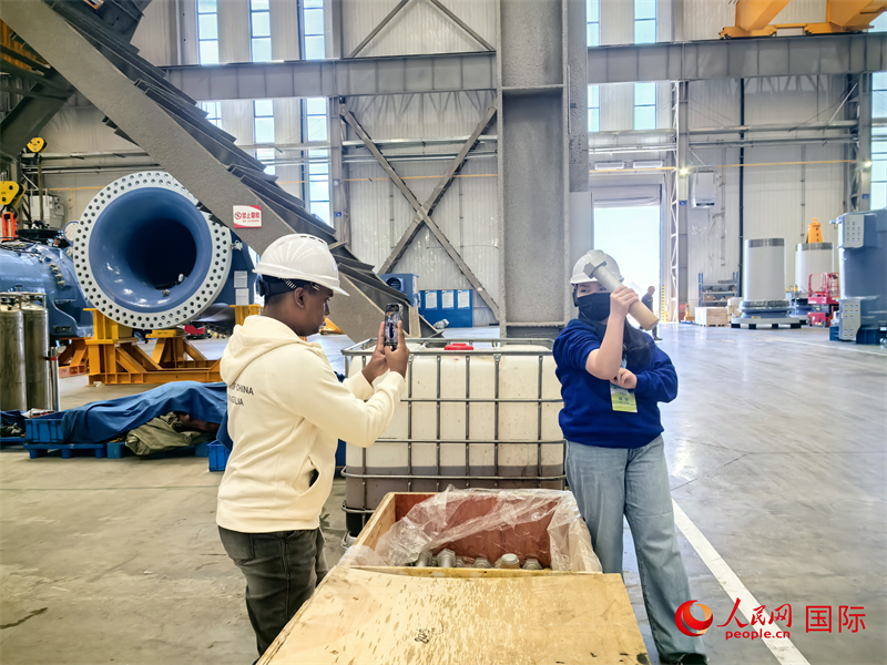 外媒記者掂量廠房?jī)?nèi)的巨型螺栓。人民網(wǎng) 楊春燕攝