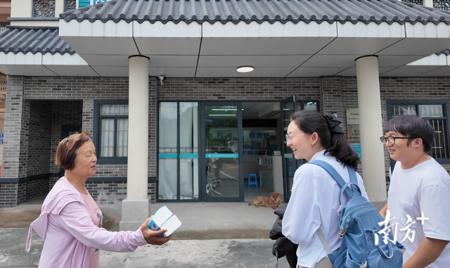 公共服務組成員王櫻潔（中）和張龍（右）在崖口村衛(wèi)生室前跟村民打招呼。