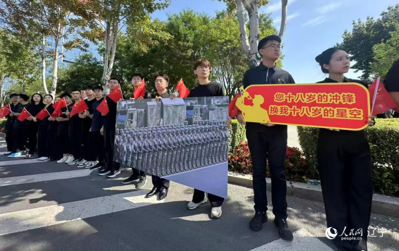 沈陽市人民廣場上，大學(xué)生們手持閱兵的圖片，告慰英烈。人民網(wǎng)記者 周頌雪攝