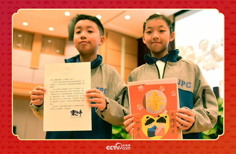圖為香港“少年警訊”成員郭宏晞（左）展示習主席回信、羅顥凝（右）展示送給習主席的賀卡并合影。