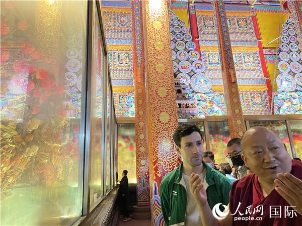 7月25日，省級非物質(zhì)文化遺產(chǎn)項目塔爾寺酥油花的代表性傳承人朋措堅參（右）在塔爾寺酥油花館講解酥油花的制作過程。人民網(wǎng) 謝瑩攝