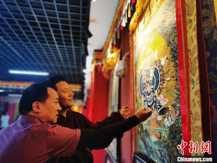圖為久美尖措展示唐卡作品?！?zhí)砀?攝
