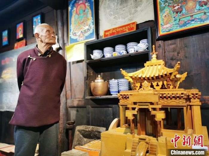 圖為古堡內(nèi)的藝人桑杰展示自己的雕刻作品?！?zhí)砀?攝