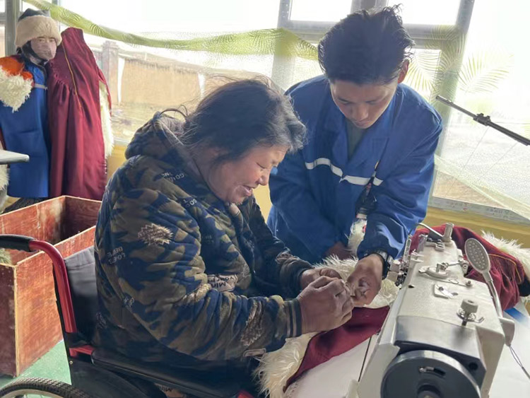 扎西奪爾登幫助殘疾員工裁剪。阿壩州文明辦供圖