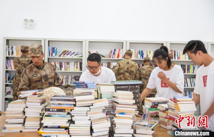 圖為志愿者們和邊防戰(zhàn)士整理圖書?！詵| 攝