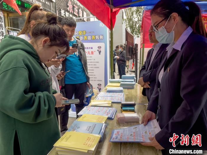 圖為工作人員正在向路過(guò)市民介紹國(guó)家反詐中心軟件的功能?！≈x牧 攝