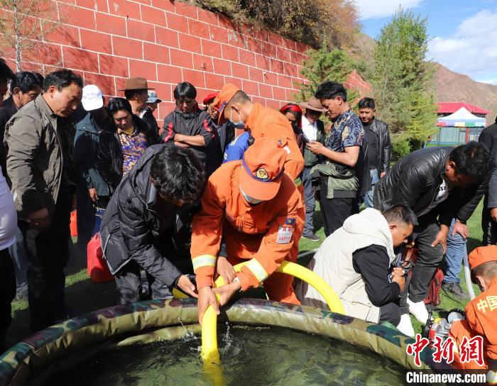 圖為森林消防員為護(hù)林員講解滅火裝備的使用方法?！〔际猩窒乐ш?duì) 供圖