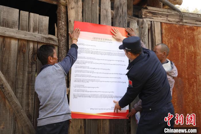 圖為亞?wèn)|邊檢站民警與駐地邊民群眾共同張貼國(guó)家安全知識(shí)教育海報(bào)?！?wèn)|邊檢站 供圖