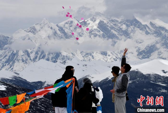 圖為5月14日，游客在西藏林芝色季拉山觀景臺拋灑“隆達(dá)”(風(fēng)馬旗，藏族民眾的一種祈福方式)。　李林 攝