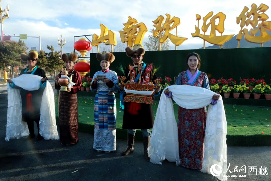 扎西曲登社區(qū)的居民在“山南歡迎您”標(biāo)志前，手持潔白哈達(dá)和切瑪，列隊迎接來自區(qū)內(nèi)外的游客，用最隆重的禮儀開啟一場沉浸式藏歷新年民俗體驗之旅。人民網(wǎng)記者 吳雨仁攝