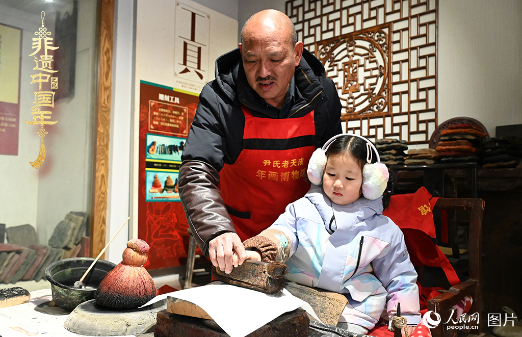 2025年1月27日，河南開封朱仙鎮(zhèn)木版年畫藝人尹國法指導(dǎo)小朋友研習(xí)年畫印制技藝。朱仙鎮(zhèn)木版年畫源自漢唐壁畫藝術(shù)，是中國木版年畫的鼻祖。2006年5月20日，朱仙鎮(zhèn)木版年畫經(jīng)國務(wù)院批準(zhǔn)列入第一批國家級非物質(zhì)文化遺產(chǎn)名錄。人民網(wǎng)記者 王玉興攝