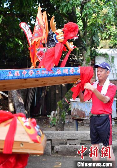 圖為5月29日，長(zhǎng)樂(lè)江田鎮(zhèn)村民為即將入水的新龍舟系紅布。　張斌 攝