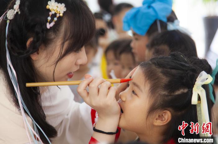 圖為老師在孩子們額頭上點(diǎn)上雄黃，驅(qū)邪辟禍?！《^生 攝