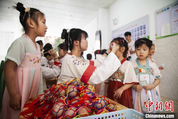 圖為幼兒園的老師們穿上漢服為小朋友們戴上彩蛋，寓意著幸福安康。　董觀生 攝
